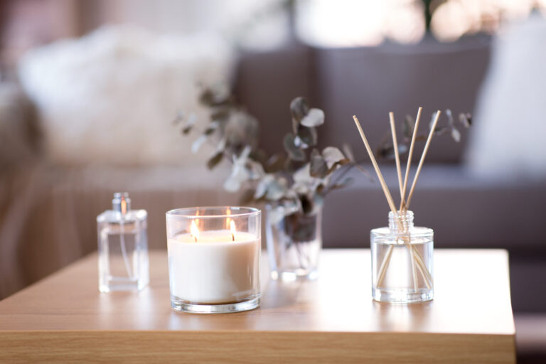 Burning candle and incense on wooden coffee table in living room.