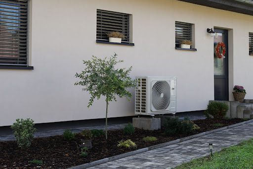 A heat pump compressor unit out front out a home.
