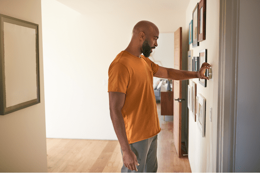Homeowner changing thermostat settings in McKinley, TX, home.