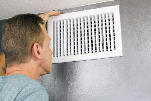 A man looking at air ducts in a home.